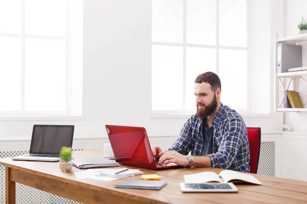 Joven hombre de negocios que trabaja con el ordenador portátil en la oficina blanca moderna — Foto de Stock