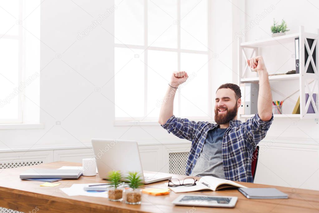 Young happy businessman in office with computer