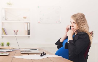 Hamile iş kadını telefonda konuşurken iş başında