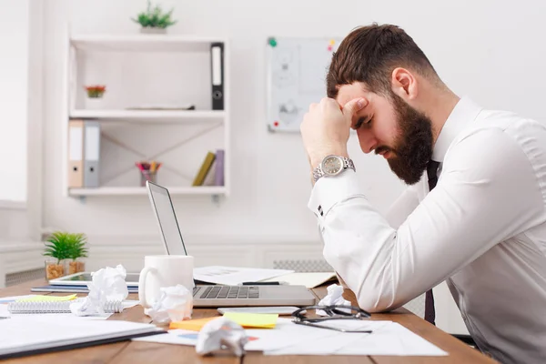 Young exhausted businessman thinking about solution in white office. Papers on the desk — Stock Photo, Image