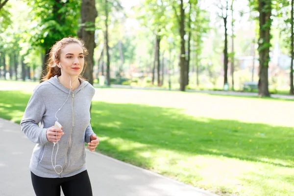Mujer joven corriendo en el parque verde, espacio para copiar — Foto de Stock