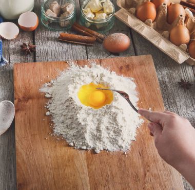 Kadın baker yumurta, tereyağı ve un ile hamur yapar