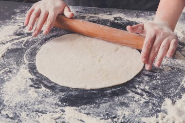 Fırın kavramı. El hamur siyah arka plan üzerine rulo..