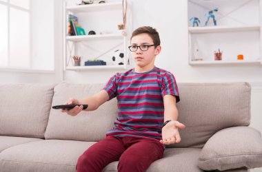 Televizyon izlerken, uzaktan kumanda ile genç çocuk