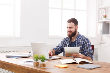 Genç modern beyaz ofiste dizüstü bilgisayar kullanan adam gülümsedi