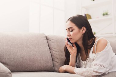 Genç kız kanepe üzerinde mobil yalan konuşuyor