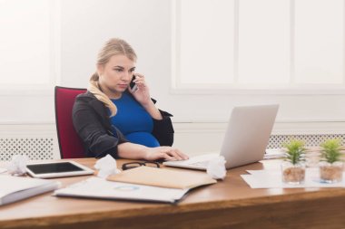 Hamile iş kadını telefonda konuşurken iş başında