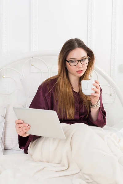 Mujer lee desde la tableta PC en la cama, espacio de copia — Foto de Stock