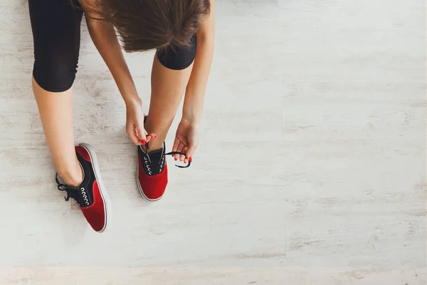 Mujer atando encaje en zapatos deportivos vista superior — Foto de Stock