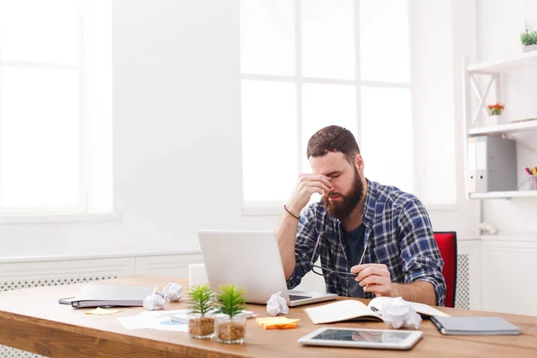 Cansado, excesso de trabalho empresário com laptop no escritório branco moderno — Fotografia de Stock