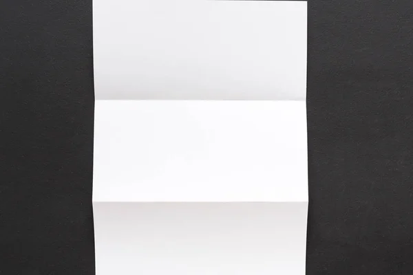 White folded sheet of paper on black background