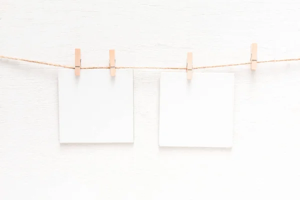 Tarjetas blancas en blanco en la cuerda, fondo de pared ligero — Foto de Stock