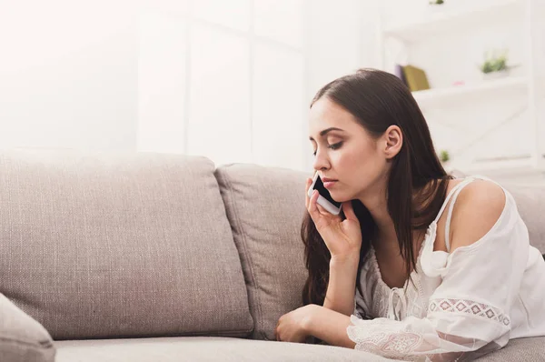 Genç kız kanepe üzerinde mobil yalan konuşuyor