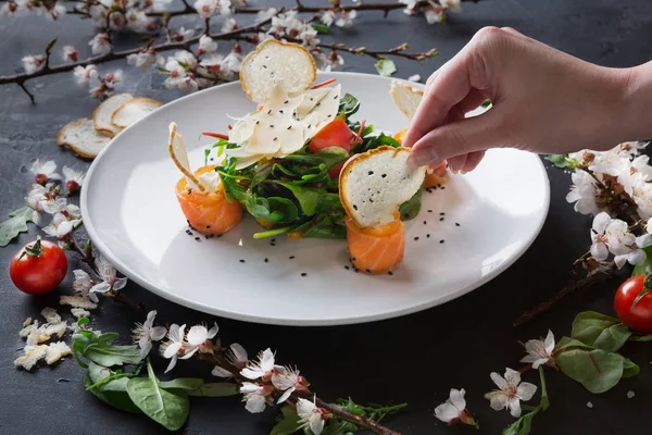 Kvinnan försöker restaurang maträtt på vit platta på grå bakgrund — Stockfoto