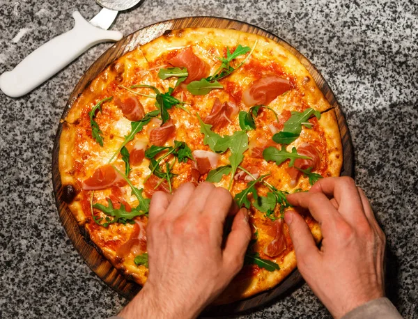 Rucola zu Pizza hinzufügen, Draufsicht — Stockfoto