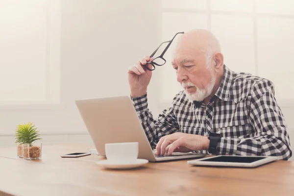 Besorgter Senior nutzt Laptop zu Hause — Stockfoto