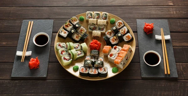 Set sushi maki en broodjes op zwarte rustiek hout — Stockfoto