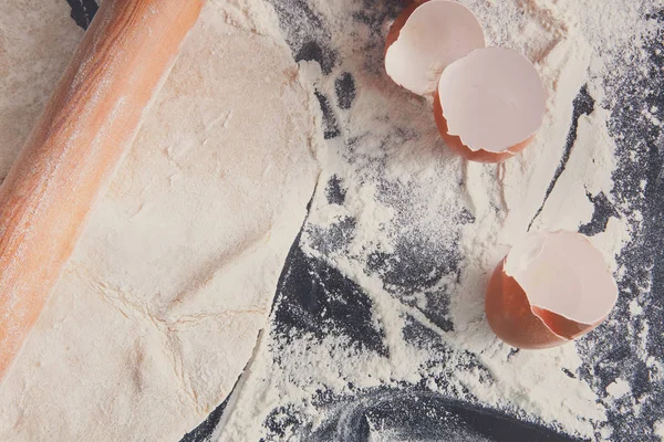 Baking concept. Hands roll dough and eggshell on black backgroun — Stock Photo, Image