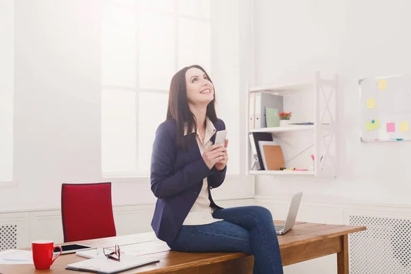 Geschäftsfrau sitzt auf Holztisch im Büro — Stockfoto