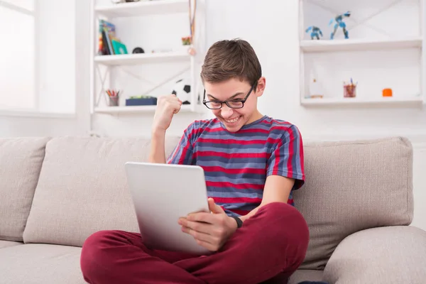 Tonårspojke som använder digitala tablett på soffan hemma — Stockfoto