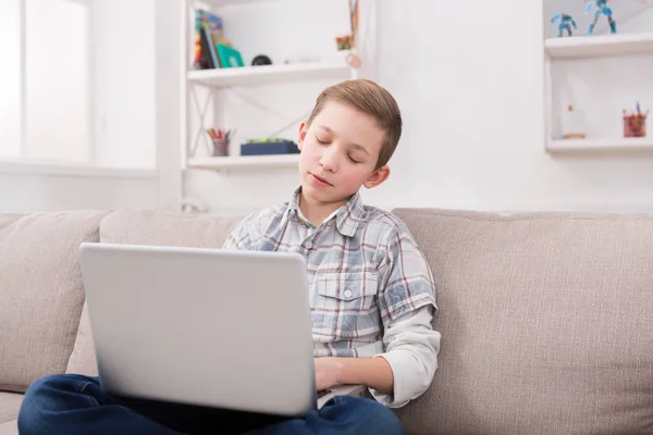 Мальчик-подросток в Интернете на ноутбуке на диване дома — стоковое фото