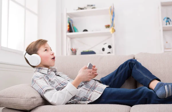 Мальчик-подросток наслаждается музыкой в наушниках дома — стоковое фото