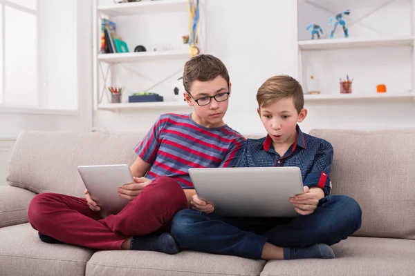 Twee tienerjongens met gadgets op de Bank thuis — Stockfoto