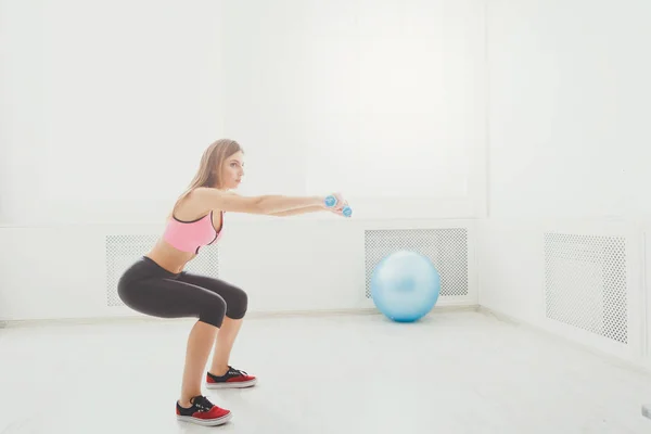 Mooie jongedame in sportkleding doen van de squat — Stockfoto