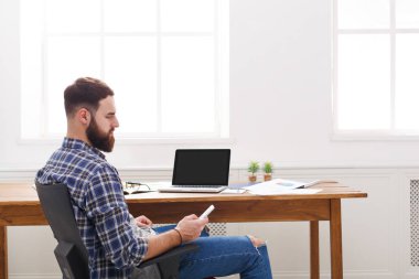 Genç başarılı işadamı dizüstü bilgisayar ve cep telefonu modern beyaz ofis içinde sakal