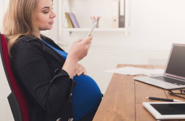 Ofiste Smartphone kullanan genç hamile kadın