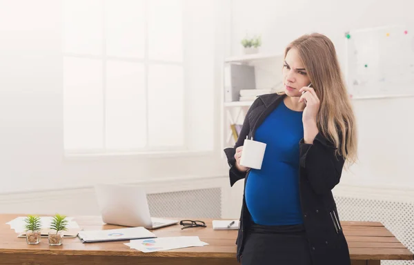 Pregnant business woman talking on phone with cup — Stock Photo, Image