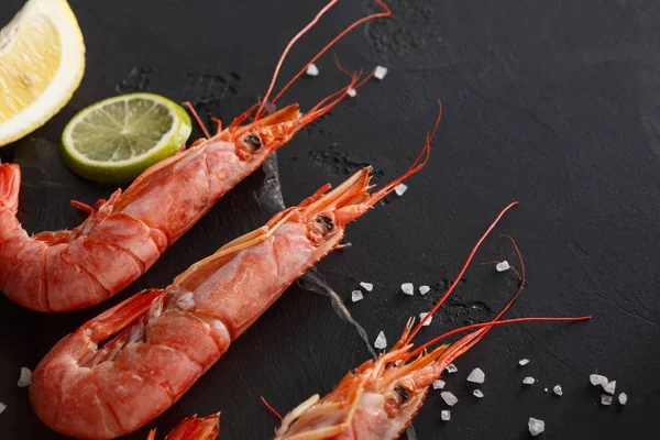 Siyah arka plan üzerine limon ve tuz ile karides