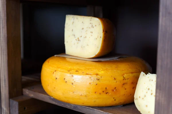Τυρί γκούντα ως ρόδα και κομμάτι στον ξύλινο ράφι ένα κατάστημα ειδών παντοπωλείου — Φωτογραφία Αρχείου