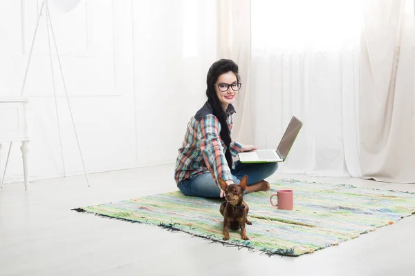 Junges Mädchen auf dem Boden mit Laptop und Hund — Stockfoto