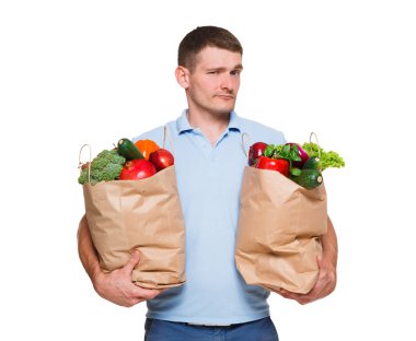 Genç adam alışveriş torbaları beyaz arka plan üzerinde izole sebze dolu holding.