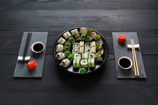 Set sushi maki en broodjes op zwarte rustiek hout — Stockfoto