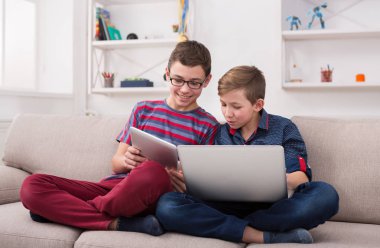 İki genç çocuklar evde kanepede gadget'lar ile