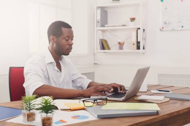 Genç siyah işadamı modern beyaz ofis içinde laptop ile çalışma