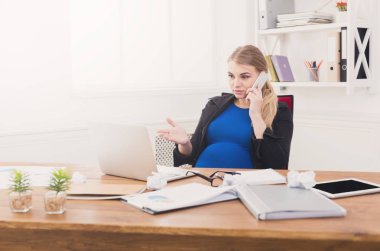 Hamile iş kadını telefonda konuşurken iş başında