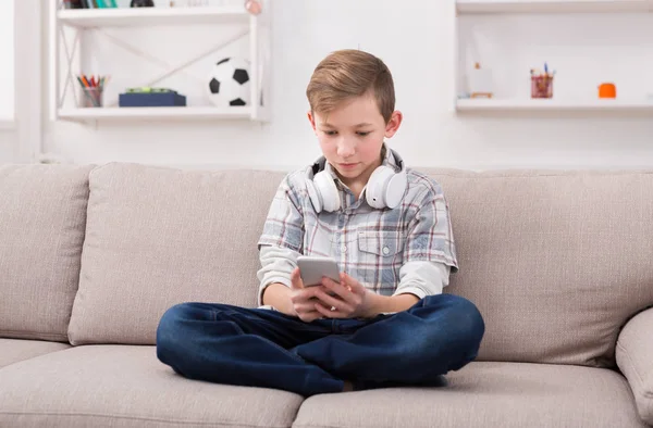 Tonåringen meddelanden online på smartphone i vardagsrummet hemma — Stockfoto