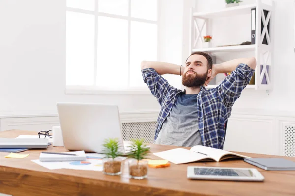 Genç adam modern beyaz ofis içinde laptop ile rahat