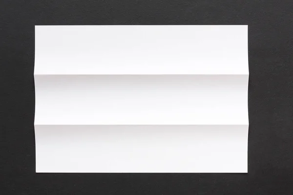 Bílá složený list papíru na černém pozadí — Stock fotografie