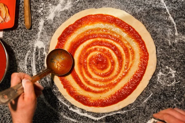 Chef verteilt Tomatenmark auf Pizzaboden — Stockfoto