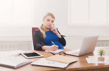 Hamile iş kadını telefonda konuşurken iş başında