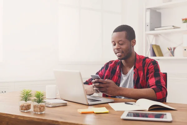 Jonge zwarte zakenman met mobiele telefoon in moderne witte kantoor — Stockfoto