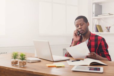 Genç işadamı okuma belgeleri siyah ve mobil modern beyaz ofisinde konuşmak