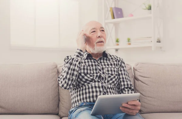 Senior man talking on phone with tablet — Stock Photo, Image