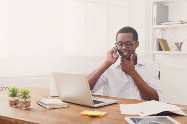 Modern beyaz ofis cep konuşurken genç siyah işadamı