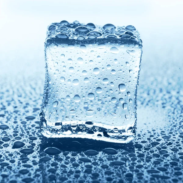 Transparenter Eiswürfel auf blauem Glas mit Wassertropfen — Stockfoto