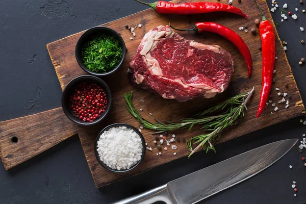 Ahşap masa başında siyah arka plan üzerinde baharatlar ile kaburga eti